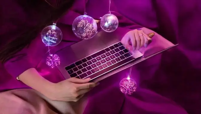 ragazza che scrive su computer con palline di natale
